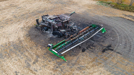 Aerial view of burnt combine harvester with fire extinguishers on grain field in rural North Dakota, taken at daytime